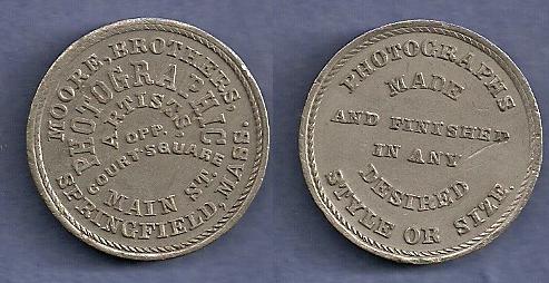 JAB-21 MOORE BROTHERS PHOTOGRAPHY Tin #2
28mm -  400 struck

Dies were cut in 1865 and presumably given to the Moore Brothers.  They are currently unaccounted for.

The Moore Brothers were jointly in Business at 441 Main Street in Springfield, Mass. from 1859 through 1877.  During the Civil War, they photographed every new recruit from Springfield and provided copies at no charge.  Between the two Brothers, they amassed more than 80,000 negatives.

The metalic composition of this piece appears to be different than that of the first example pictured.  I question whether there may have been more than one striking for the merchant?  

Although it is accepted that there were 400 pieces struck in Tin, the piece is much rarely than the mintage would indicate.  A silvered edge lettered example sold for $550 in a Hayden 8/2015 Sale.  A NGC-63 example sold for $264 in the 9/2021 Stacks sale, lot 70119
Keywords: bolen moore photography